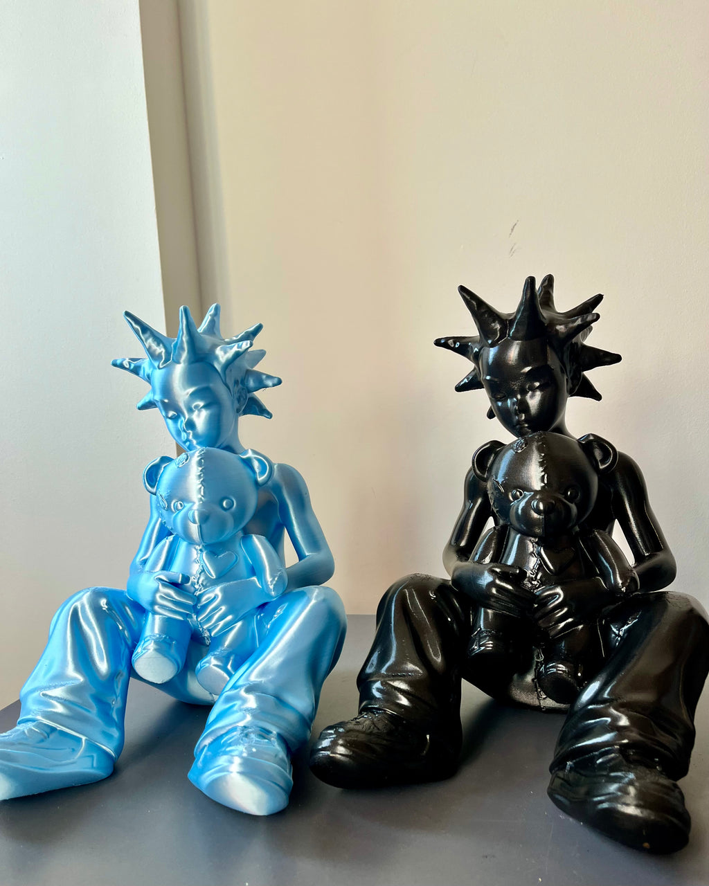 Two figurines, one blue and one black, sitting on a flat surface with a neutral background.